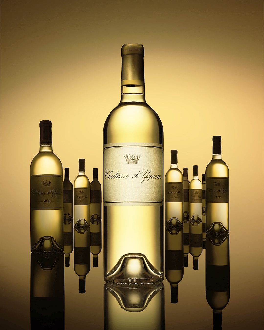 Bottles of Sauternes arranged on a reflective surface against a warm golden backdrop